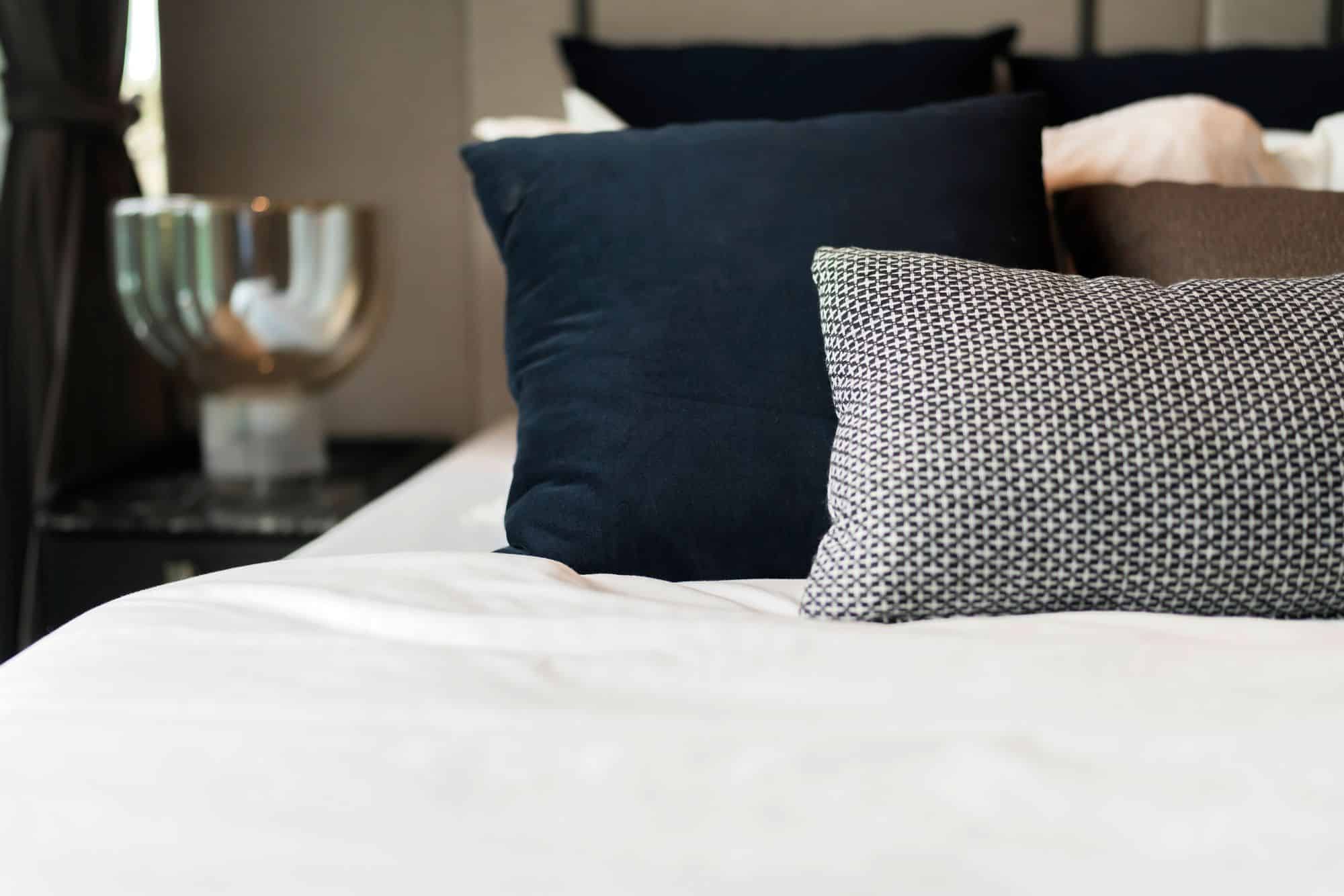 bed maid-up with clean white pillows and bed sheets in beauty room. close-up. lens flair in sunlight.home interior detail design background